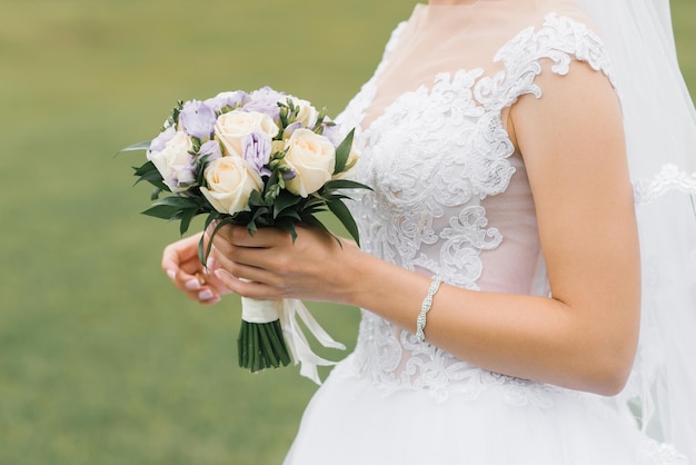 The bride's wedding bouquet of milk roses and lilac eustoms in the hands of the bride closeup