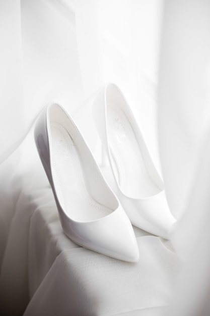 Bride's white shoes stand on white windowsill