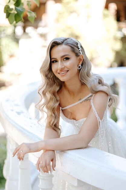 Bride sitting on a white railing in a white dress