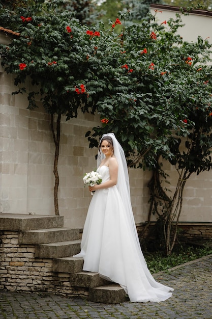 Bride standing in front of a wall with red flowers