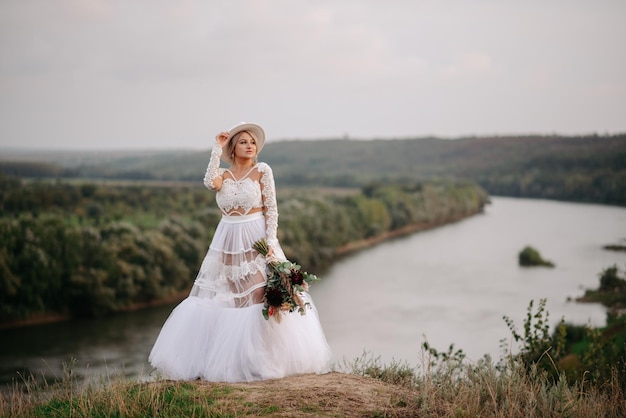 Bride standing on a hill with a river in the background