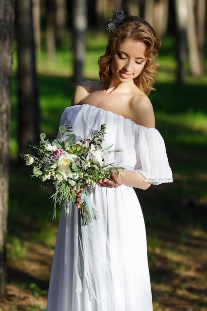 Невеста стоит и держит в руке свадебный букет