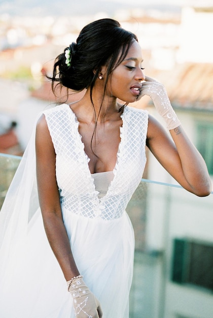 Bride stands at the glass railing on the terrace of the building