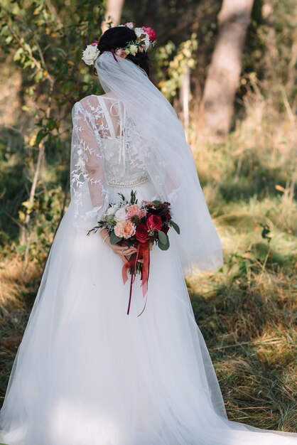 La sposa sta in un abito da sposa bianco con un bouquet