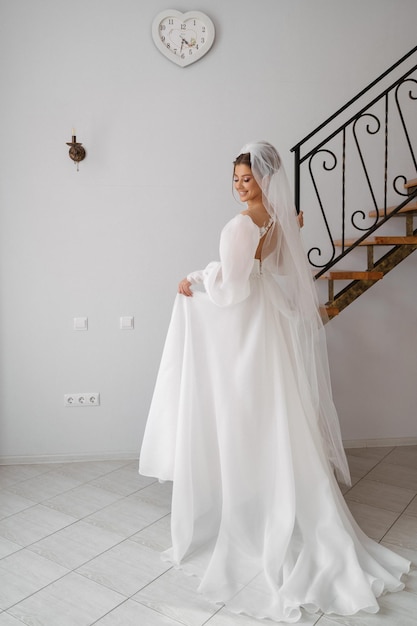 The bride stands with her back with a train climbs the stairs in the interior