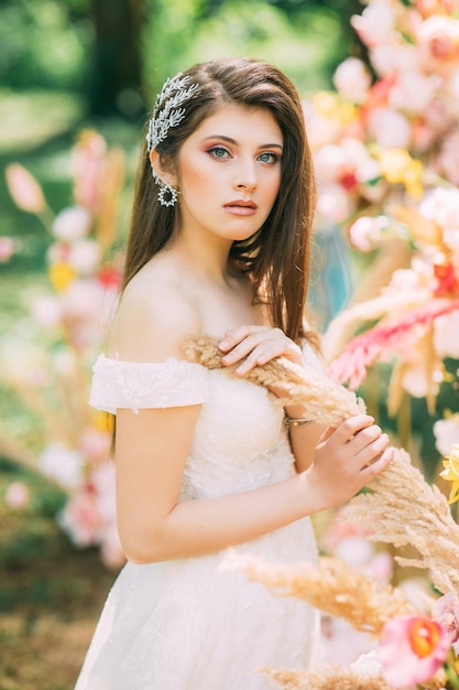 A bride in a traditional white dress with a wedding bouquet next to the wedding arch