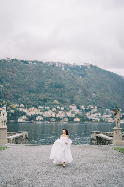 Bride walks along the road in the park looking to the side near lake como italy