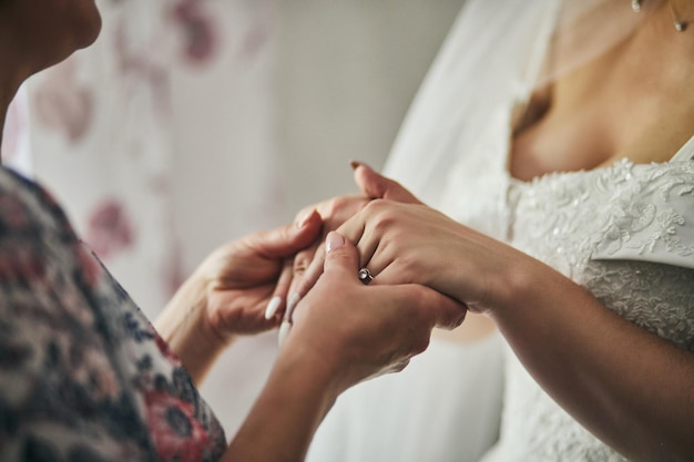 Bride on wedding day holding her mother's hands Concept of relationship between moms and daughters