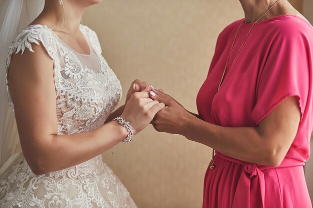 Bride on wedding day holding her mother's hands Concept of relationship between moms and daughters
