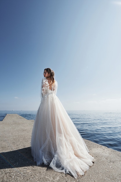 Sposa in un abito da sposa sulla spiaggia al mare