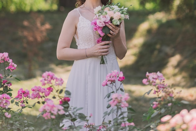 Bride in a wedding dress in flowers in the park