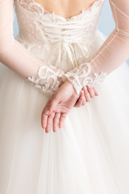 Bride in wedding dress holds hands behind her back