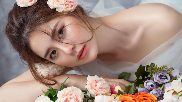 Photo 一個穿著婚的新娘躺在桌子上,上面有花.
