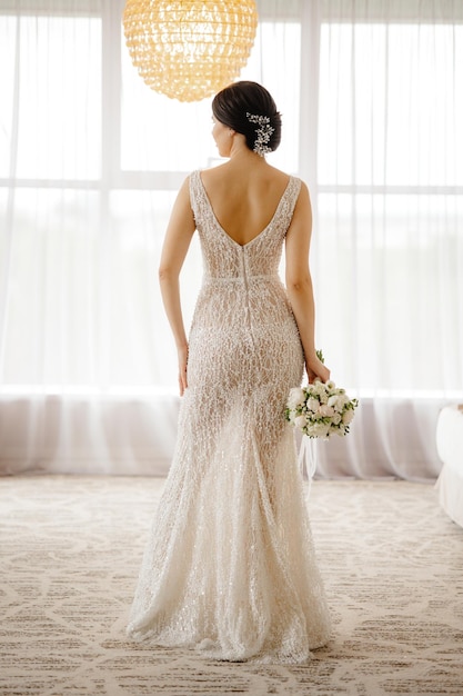 Bride in a wedding dress standing in front of a window