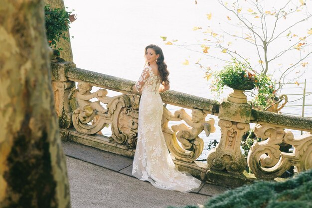 Bride in a wedding dress stands on a beautiful balcony overlooking mountains and lake