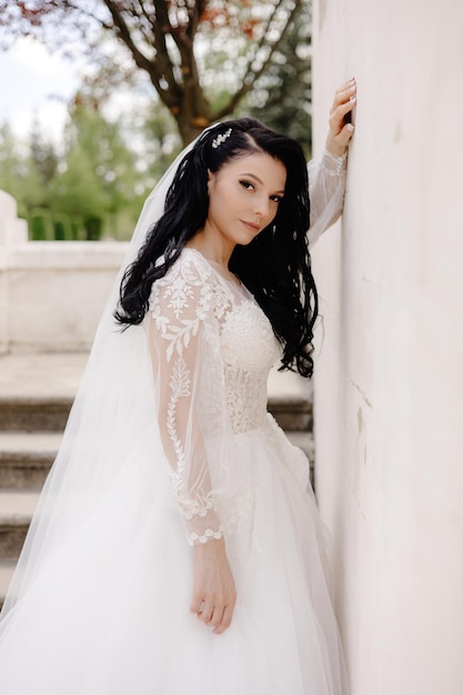 A bride in a wedding dress stands on a staircase.