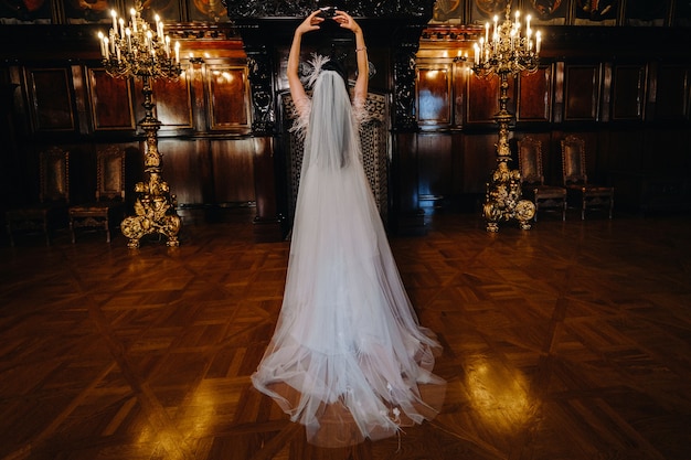 A bride in a wedding dress stands with her back in the ancient interior of the castle