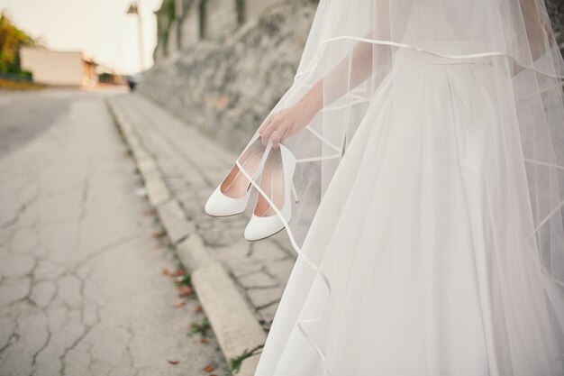 Bride in wedding dress and veil walks down the street