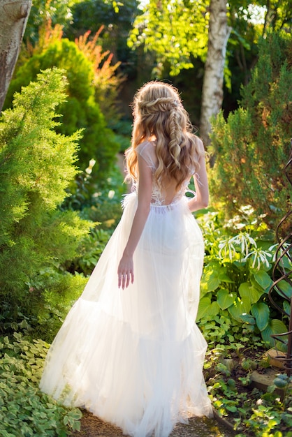 Bride in a wedding dress with her back in a green garden