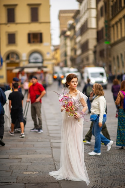 A bride in a wedding dress with a Venetian mask in her hands in Florence