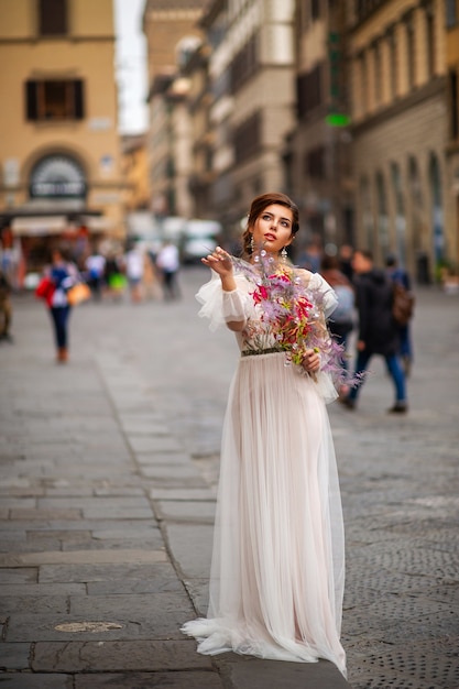 A bride in a wedding dress with a Venetian mask in her hands in Florence