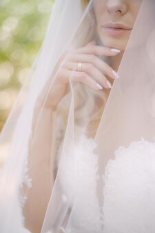 Sposa con un abito bianco coperto da un ritratto di velo