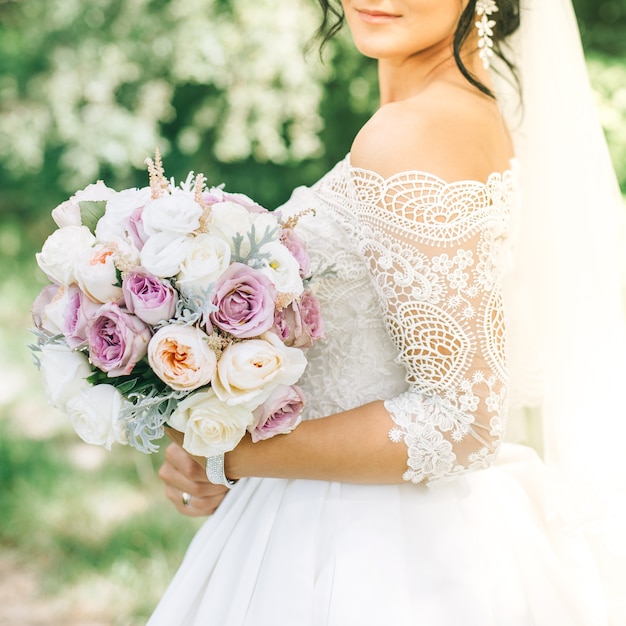 The bride in a white dress holds a beautiful bouquet