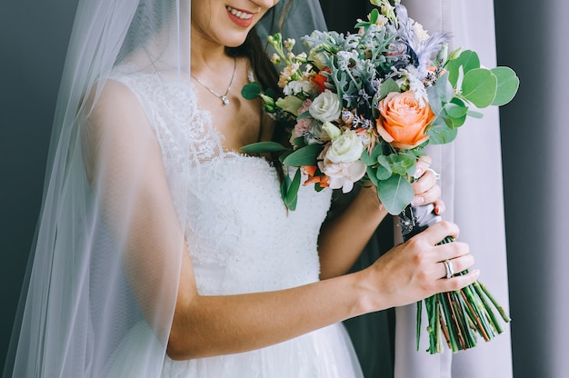 The bride in a white dress holds a beautiful bouquet