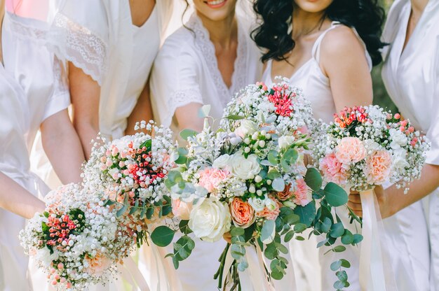 The bride in a white dress holds a beautiful bouquet