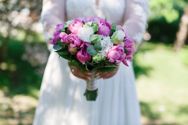 bride in white dress holds wedding bouquet of pink flowers close up stylish bouquet  in woman hands