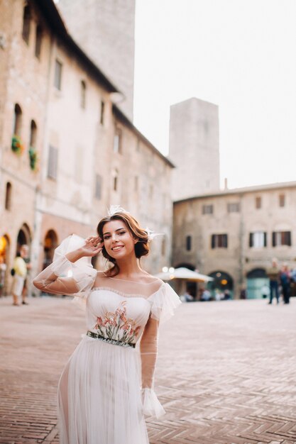 A bride in a white dress in the old town of San Gimignano.A girl walks around the city in Italy.Tuscany.