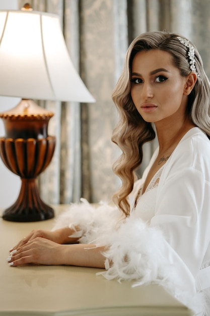 Photo a bride in a white dress sits on a table next to a lamp