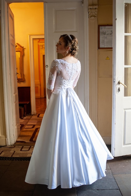 A bride in a white dress stands in a doorway.