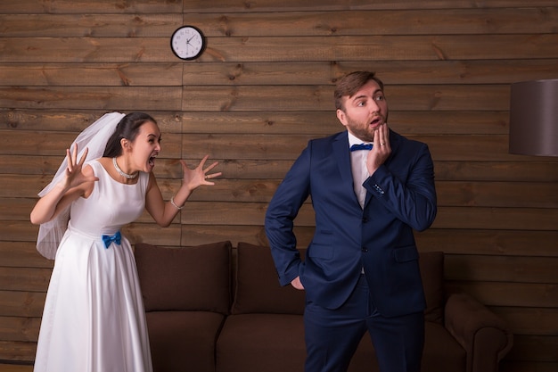 Bride in white dress and veil shouting at her groom. Newlyweds complex relationship