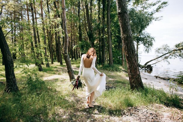 Bride in a white dress walking in the woods by the sea beach wedding conceptx9