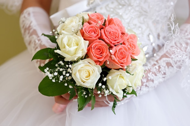 The bride in a white dress at a wedding ceremony with a bouquet of roses.