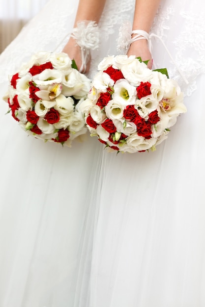 The bride in a white dress at a wedding ceremony with a bouquet of roses.