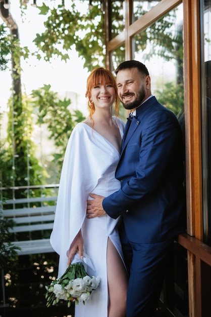 Bride in a white dress with a bouquet and the groom in a blue suit