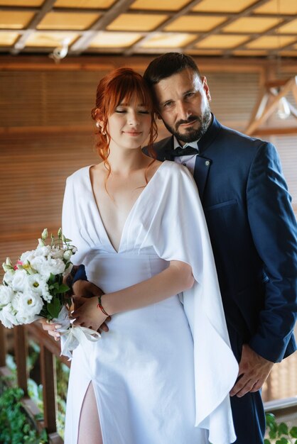 Bride in a white dress with a bouquet and the groom in a blue suit