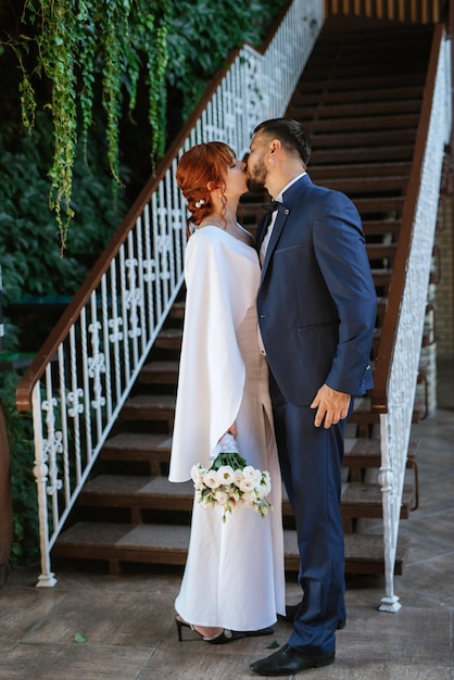 Bride in a white dress with a bouquet and the groom in a blue suit