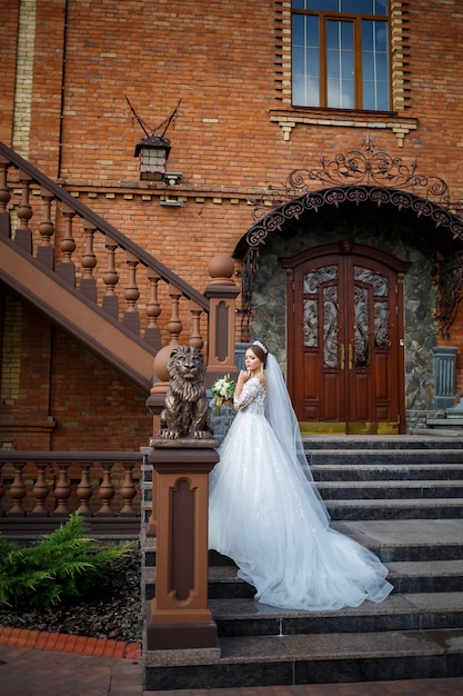 Sposa in abito bianco con un bouquet in mano e una corona in testa