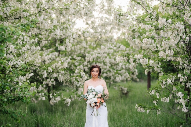 緑の森の大きな春の花束と白いドレスの花嫁