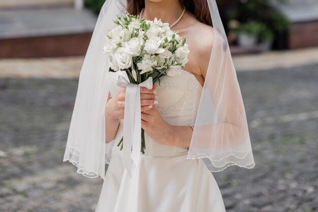 A bride in a white dress with a wedding bouquet on a city street