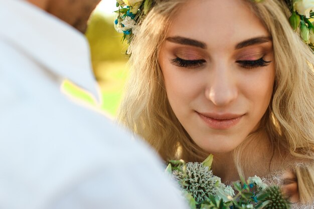 Bride in white dress and wreath and groom portrait in sunny summer day Rustic outdoor wedding