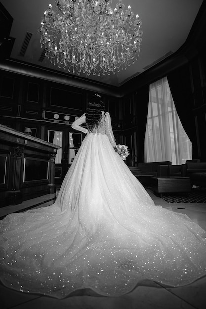 Невеста в белом длинном платье с букетом в руках стоит