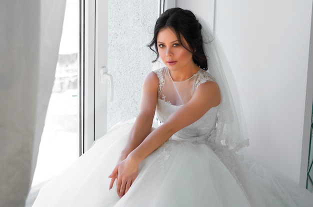 A bride in a white wedding dress in a bright room