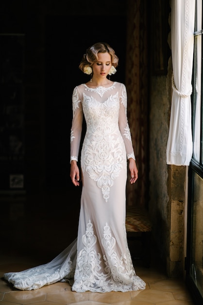 Sposa in vestito da sposa bianco che posa all'interno