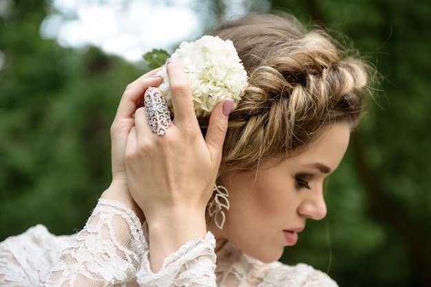 Bride with a beautiful braid on her head straightens a flower portrait