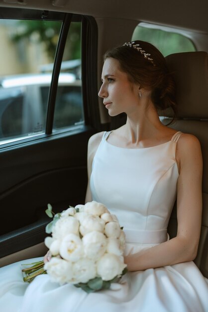 Photo bride with a black car near a glass skyscraper