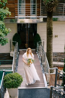 La sposa con un bouquet sta camminando sul ponte dell'hotel